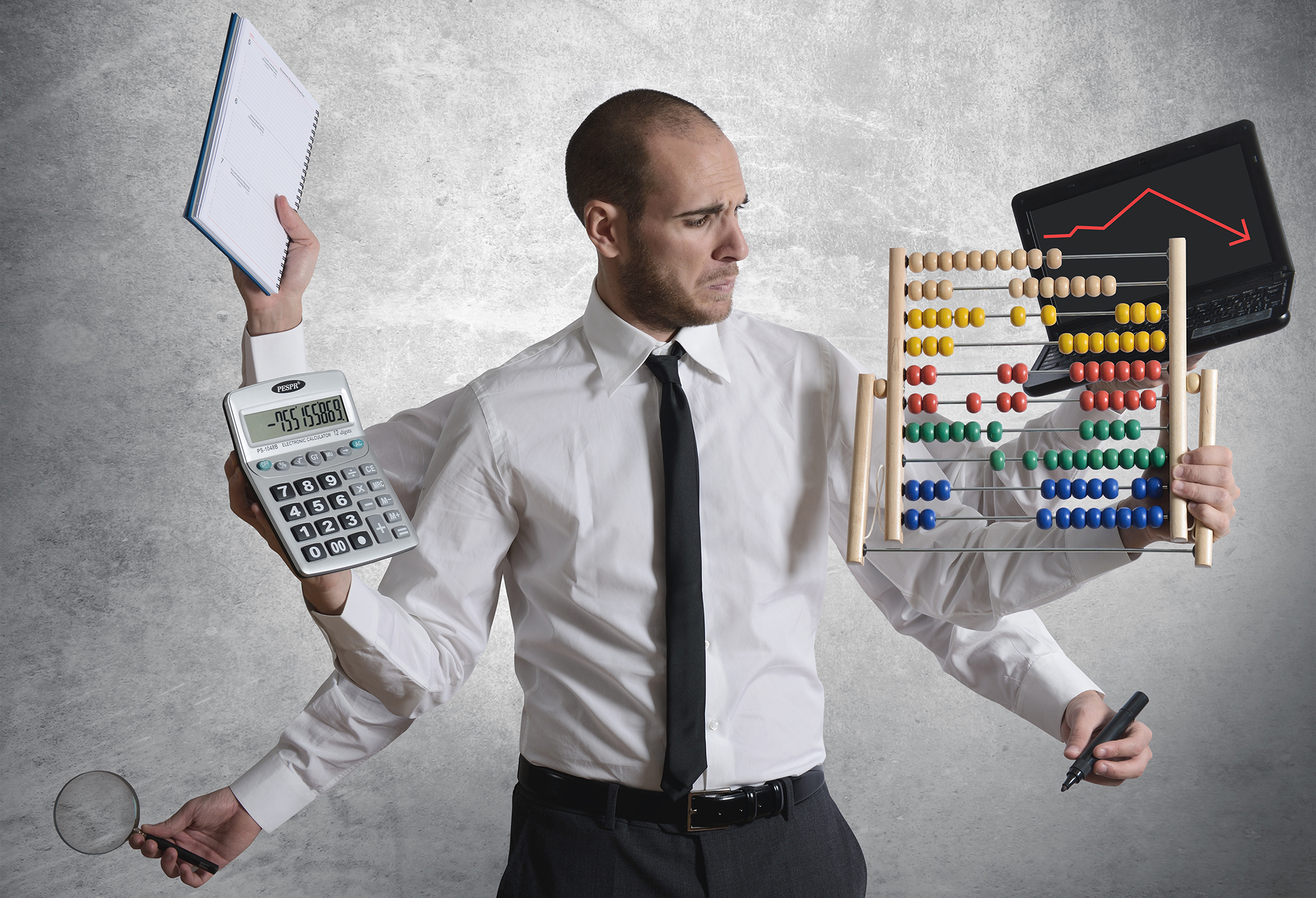 Photograph of a man looking distressed with six arms coming off of him, each holding a different item. The items include a planner book, a calculator, a magnifying glass, a laptop, an abacus, and a marker.