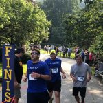 Runners with numbers on the back of their shirts participating in an event, crossing the finish line