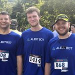 Three runners with numbers on their shirts posing for a photo