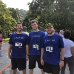 Three runners with numbers on their shirts posing for a photo