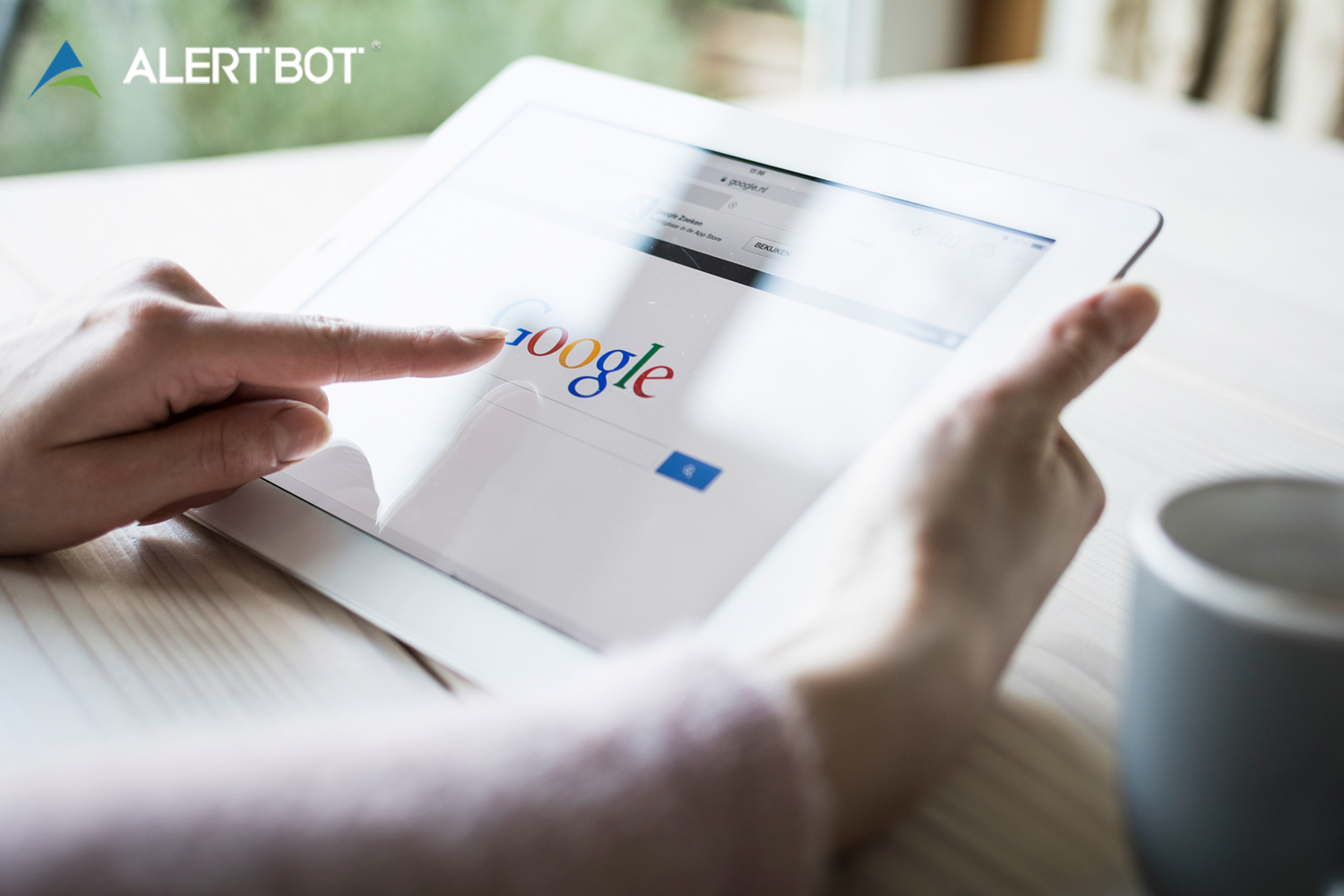 AlertBot blog titled "How Site Uptime Impacts SEO (Hint: It&rsquo;s a REALLY Big Deal)" with photo of a woman's hands pointing at a web browser featuring Google on an iPad tablet.