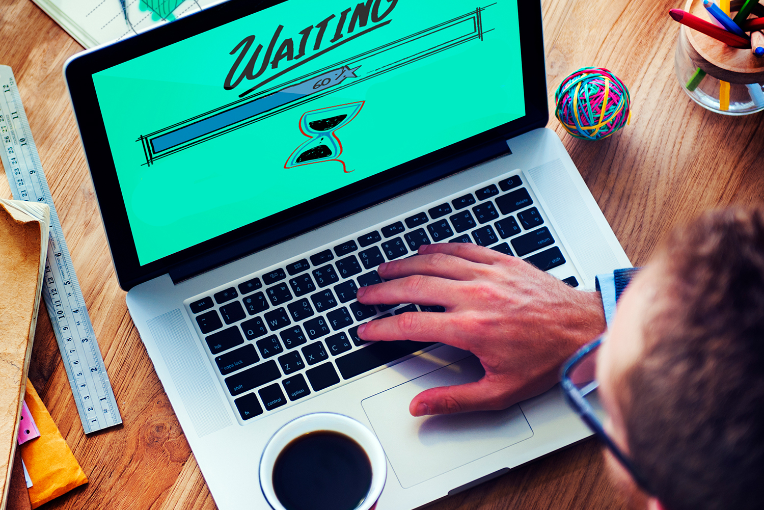 AlertBot Blog titled "Just How Bad is a Down, Slow, or Dysfunctional Website? It&rsquo;s Worse than You Think!" with an aerial view of a man with his hand on a laptop keyboard with the word "Waiting" and an hourglass on the monitor screen.