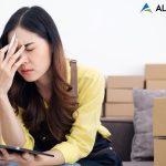 AlertBot Blog titled "7 Deadly e-Commerce Checkout Sins" with the photo of an Asian woman sitting at a laptop with a tablet in one hand and her face in the palm of the other hand looking distressed.